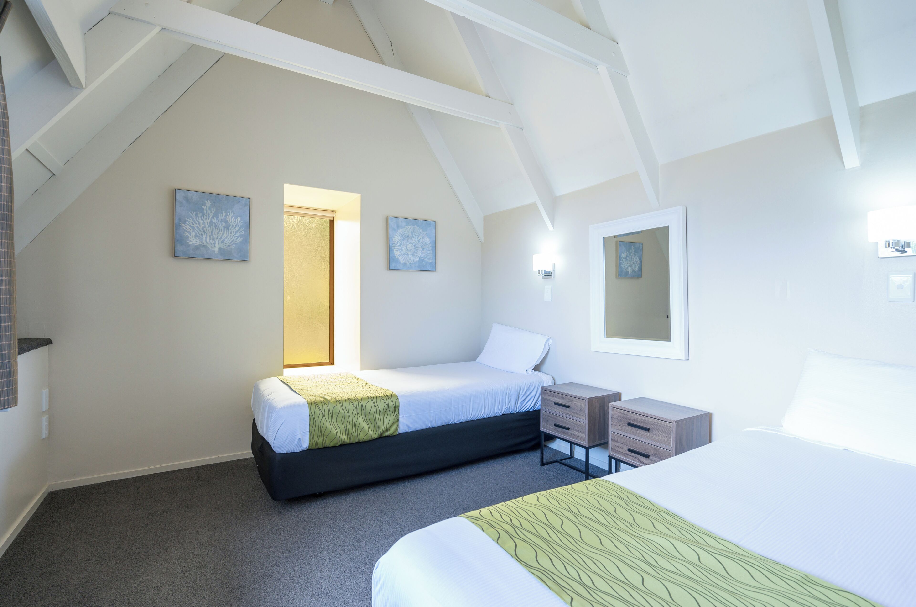Un dormitorio con dos camas, una mesita de noche, un aparador y un espejo.