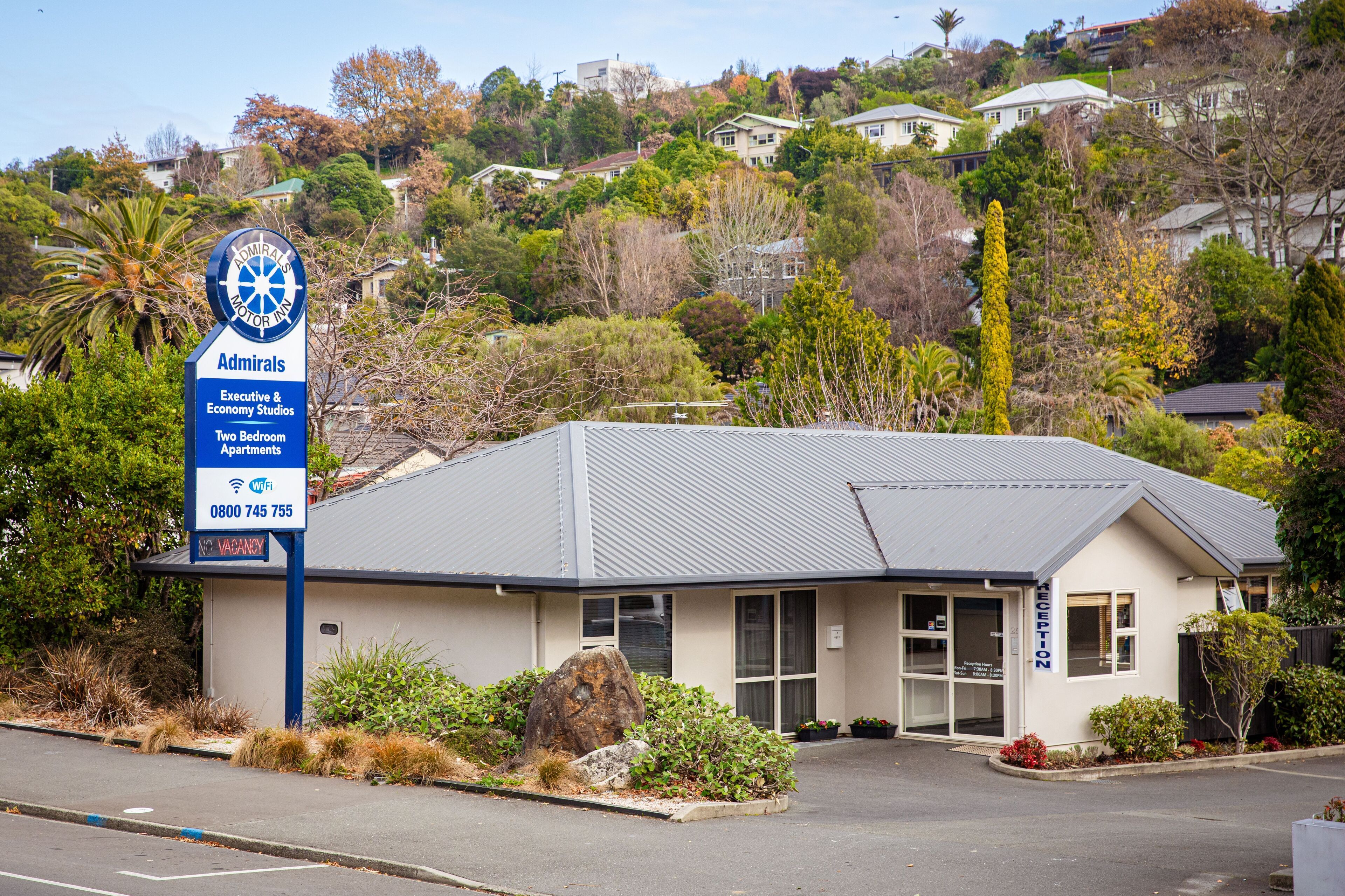A two-story building with a sign indicating it is an Admiral's Motor Inn, offering executive and economy studios, and two-bedroom apartments.