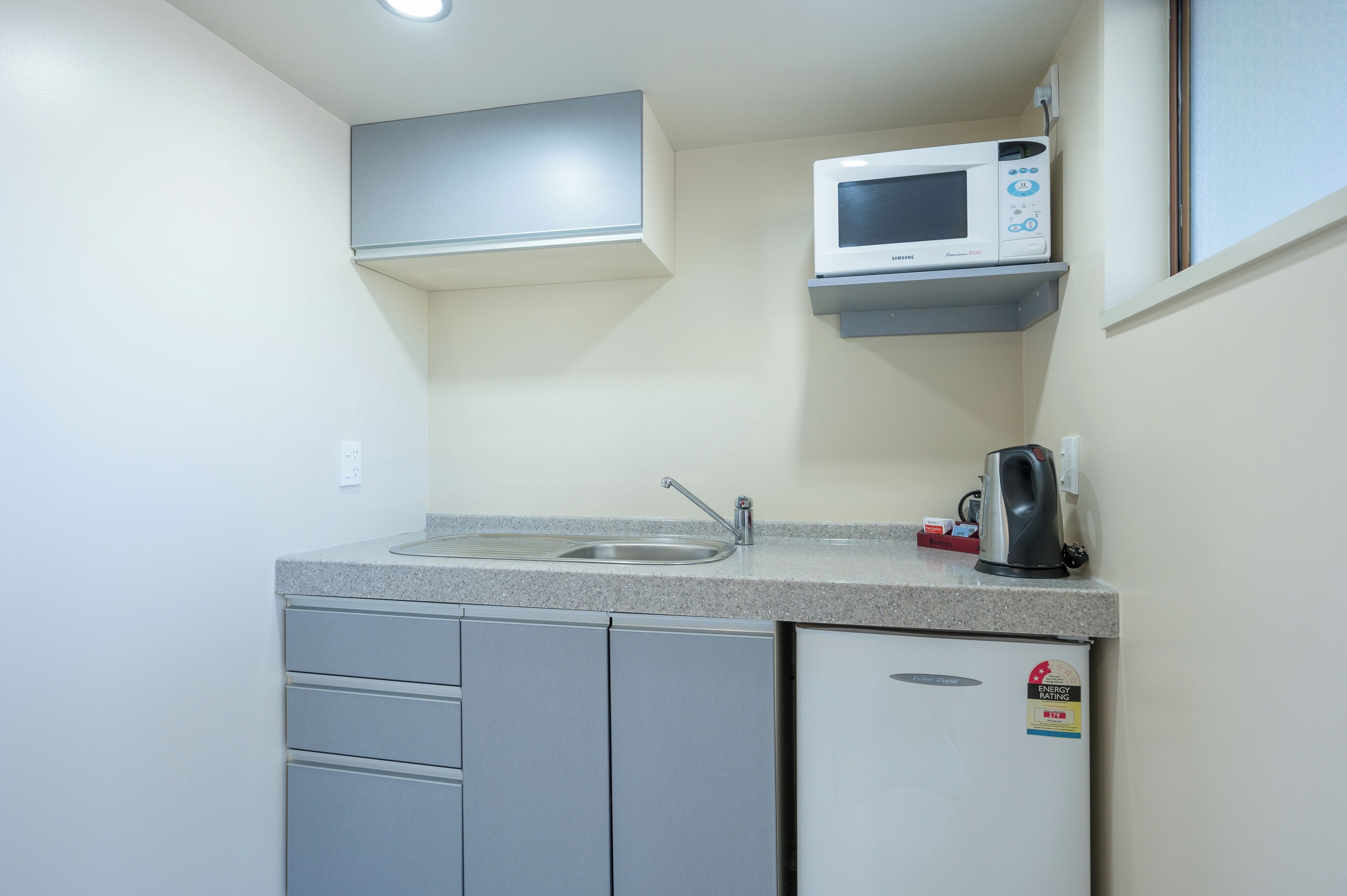 A compact kitchenette with a built-in microwave, a sink, and a small refrigerator.