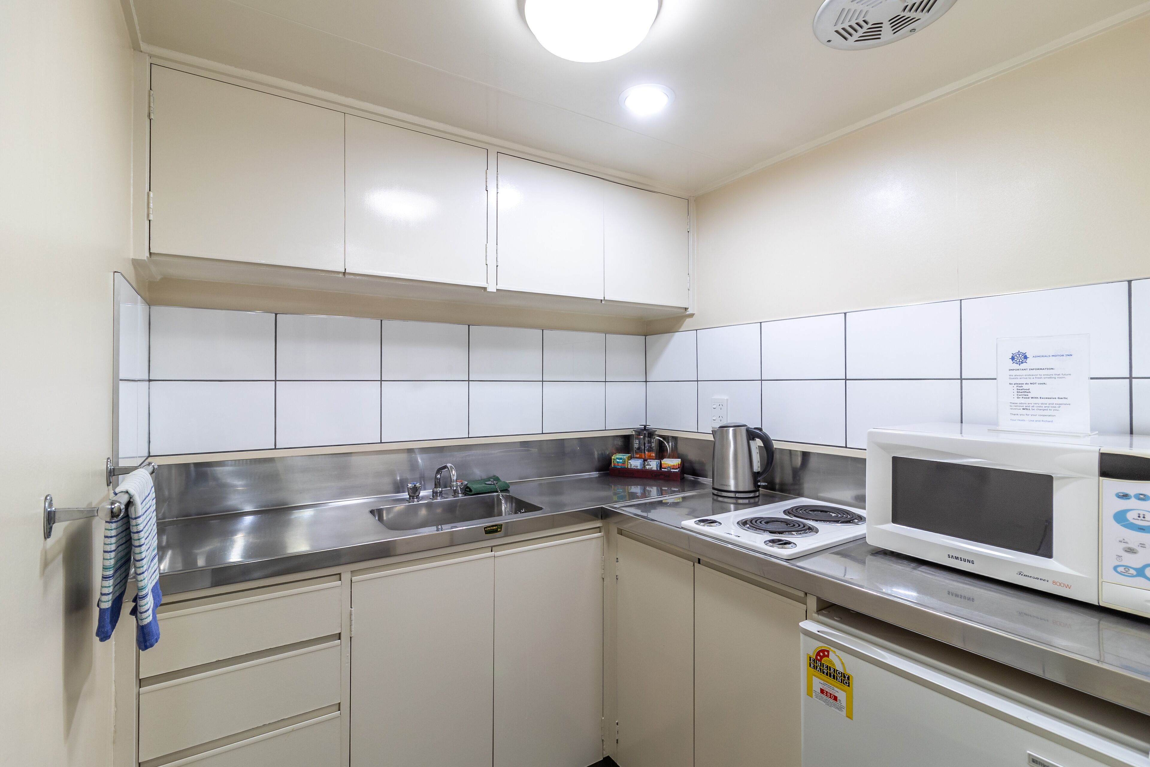 A compact kitchen with white cabinets, stainless steel appliances, and a microwave.