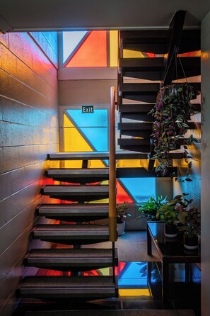 A staircase with a geometric wall design and a hanging plant.