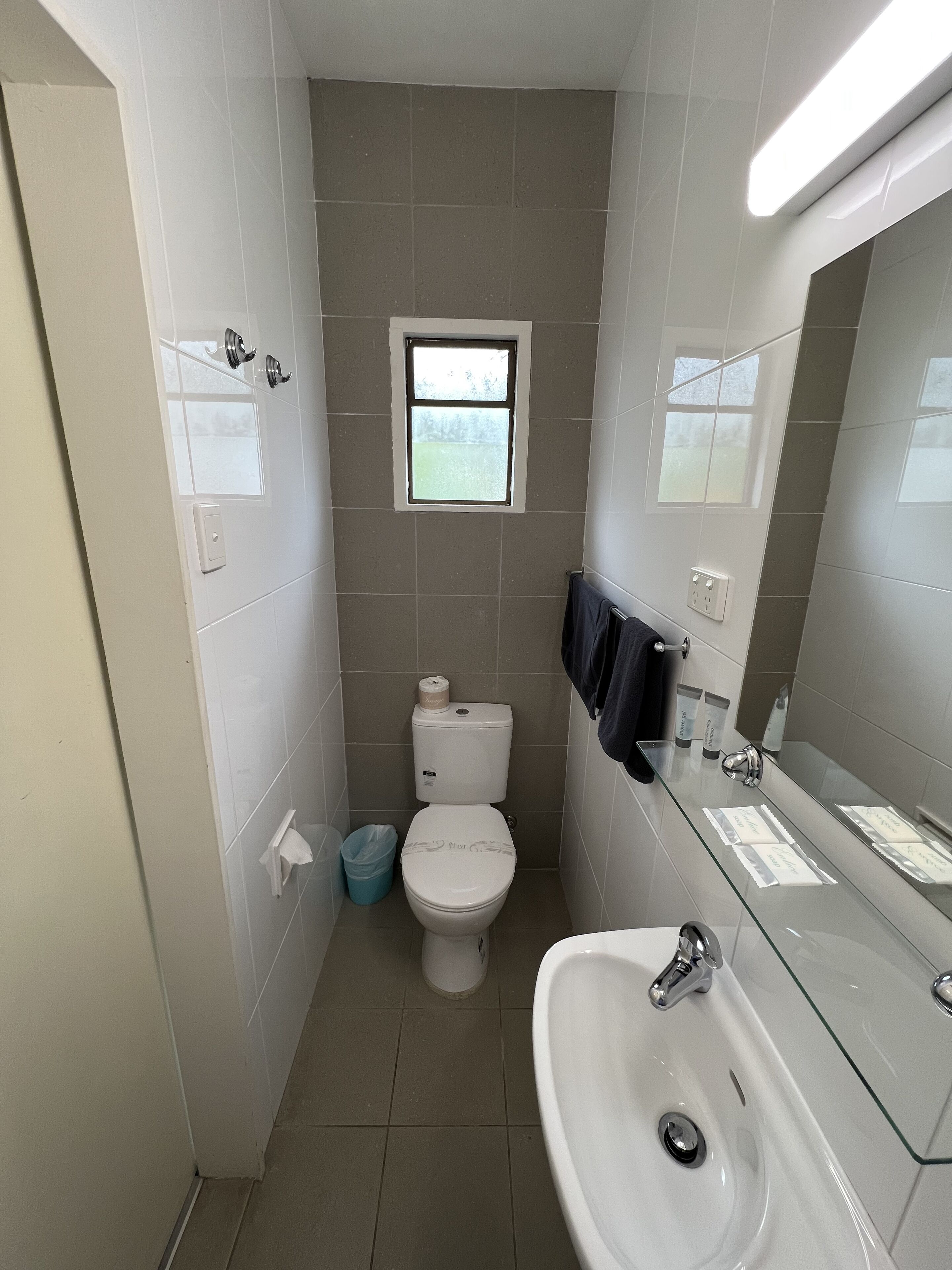 A compact bathroom with a toilet, sink, and a small window.