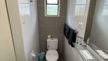 A compact bathroom with a toilet, sink, and a small window.