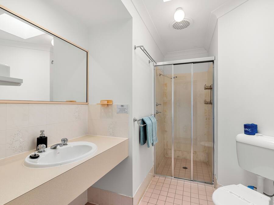 Een badkamer met een witte wastafel, spiegel en een douchecabine van glas.
