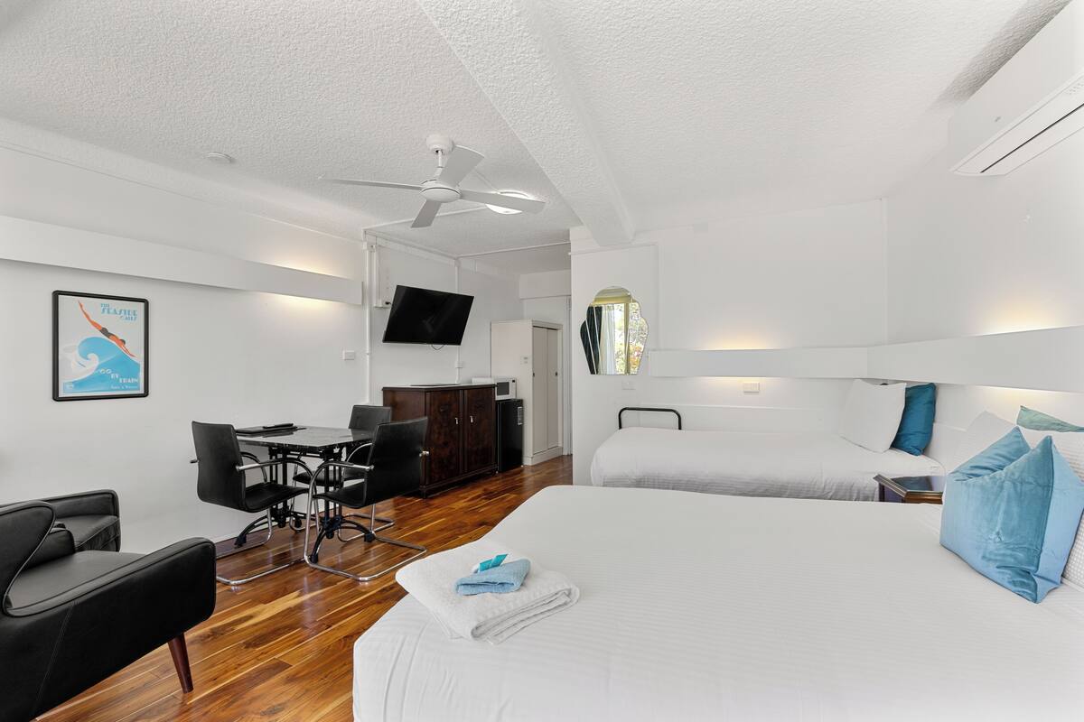 A hotel room with a bed, a desk, a chair, a television, and a ceiling fan.
