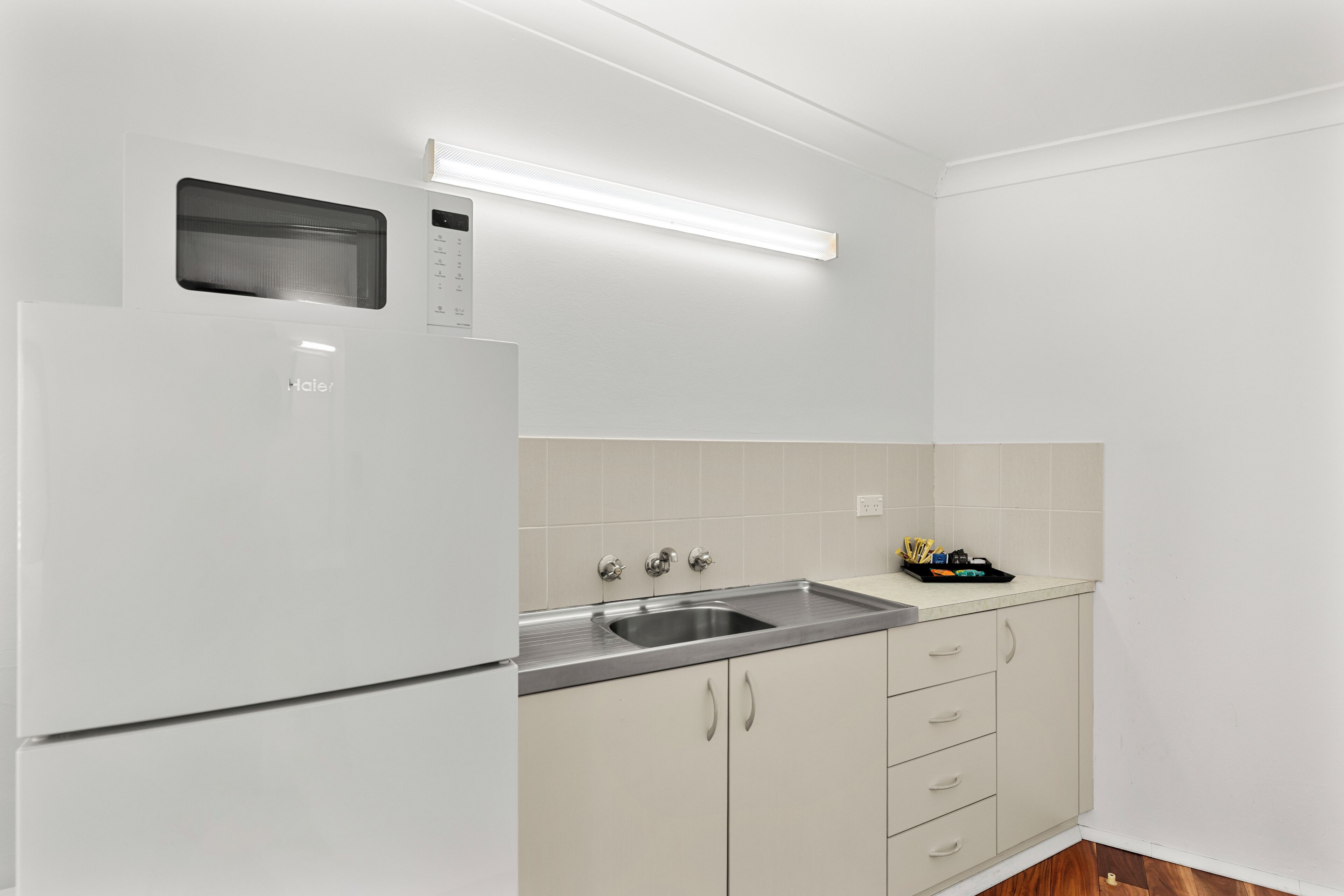 A modern kitchen with a built-in microwave, a stainless steel sink, and light-colored cabinetry.