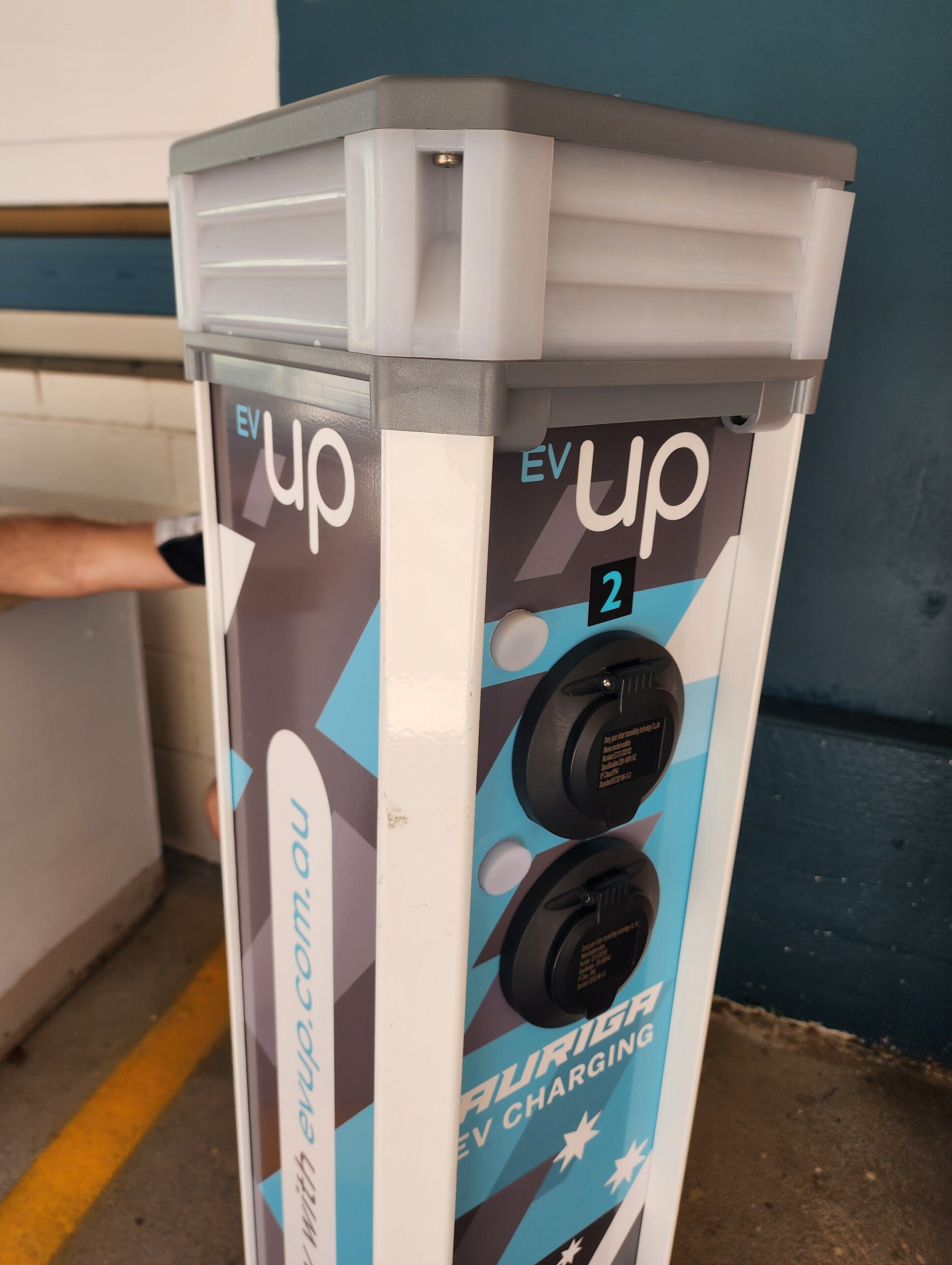 Une borne de recharge pour véhicules électriques arborant le logo « EV up » et associée au site web « evup.com.au ».