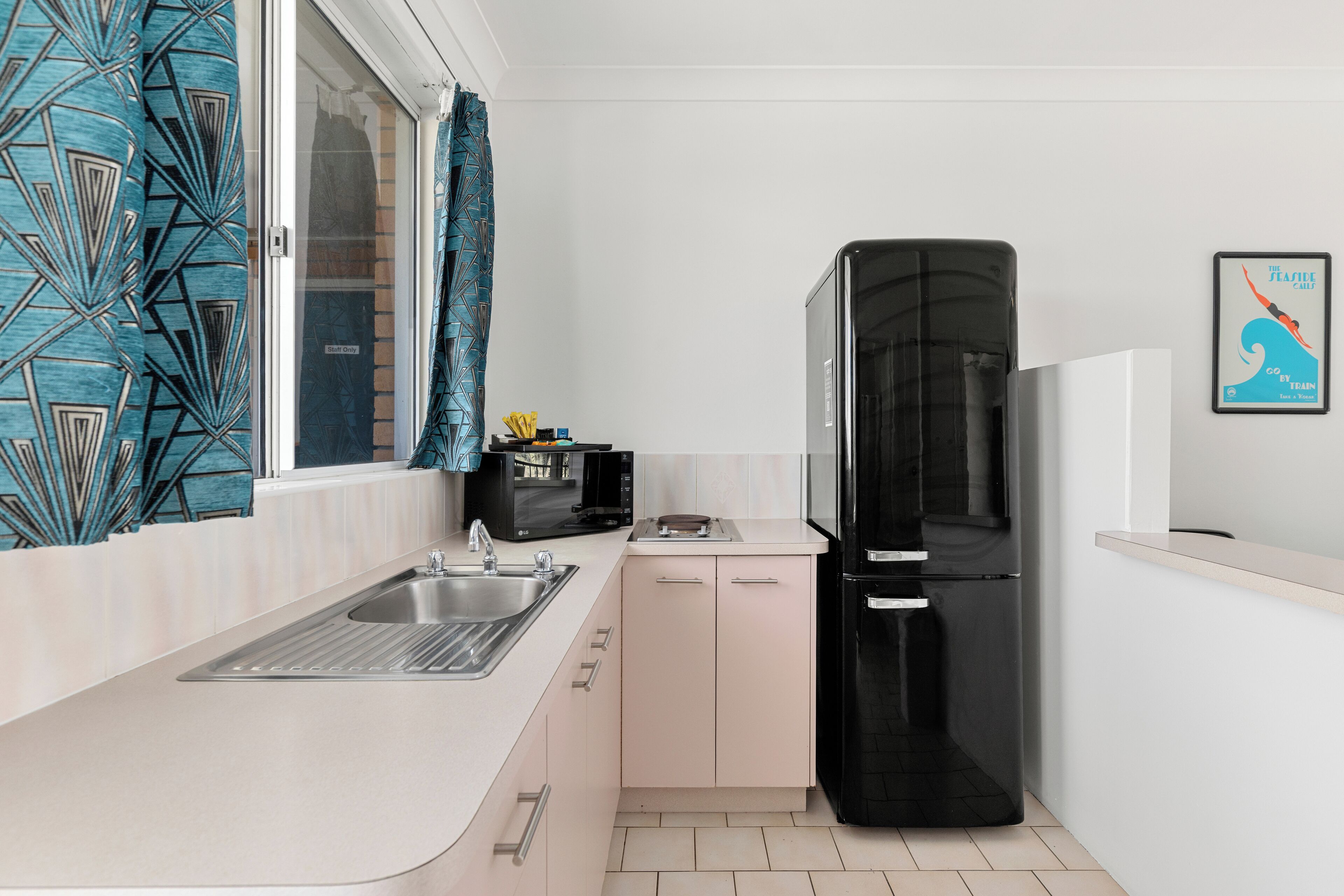 A compact kitchen with a sink, a black refrigerator, a microwave, and a small countertop.