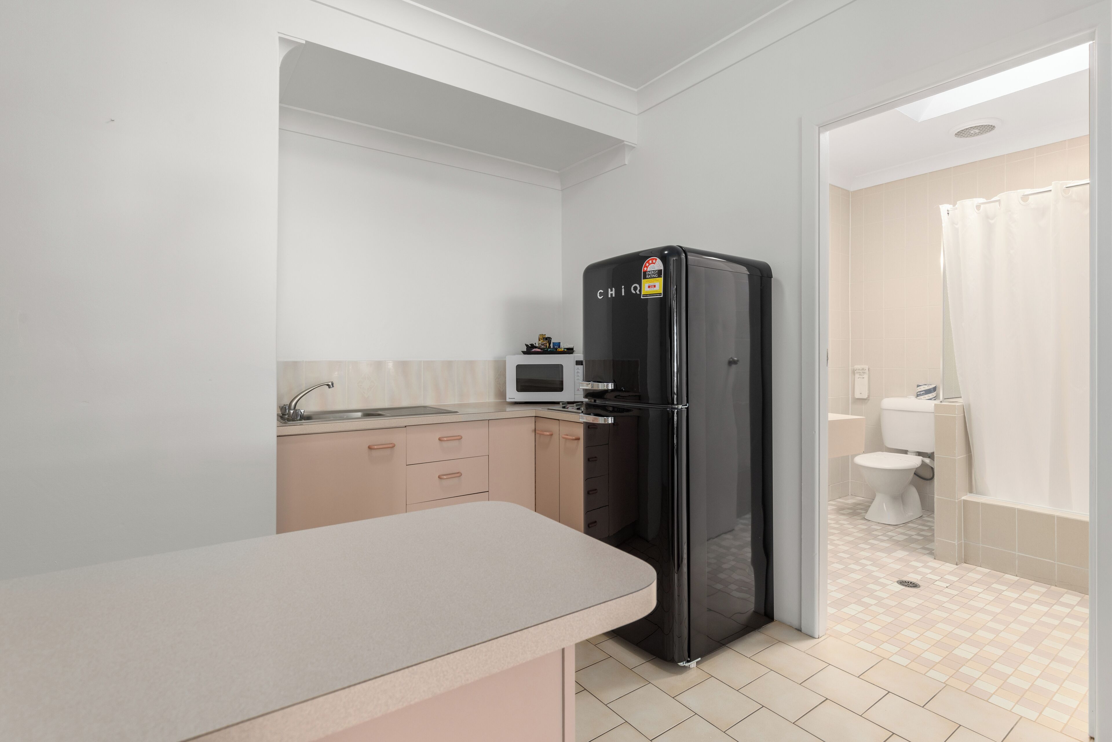 A compact kitchen with a refrigerator, microwave, and sink.