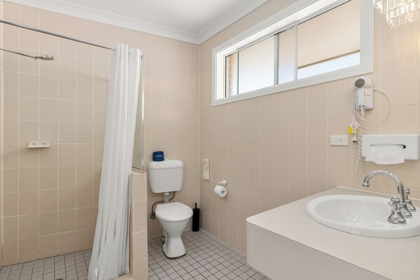 A bathroom with a shower, toilet, and sink.