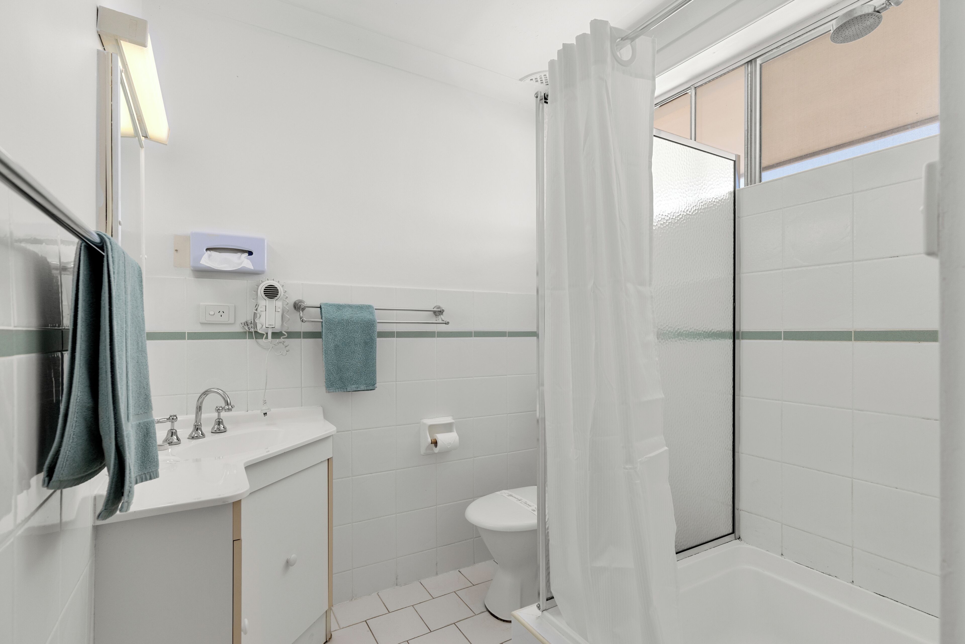 A bathroom with a sink, toilet, and shower area.