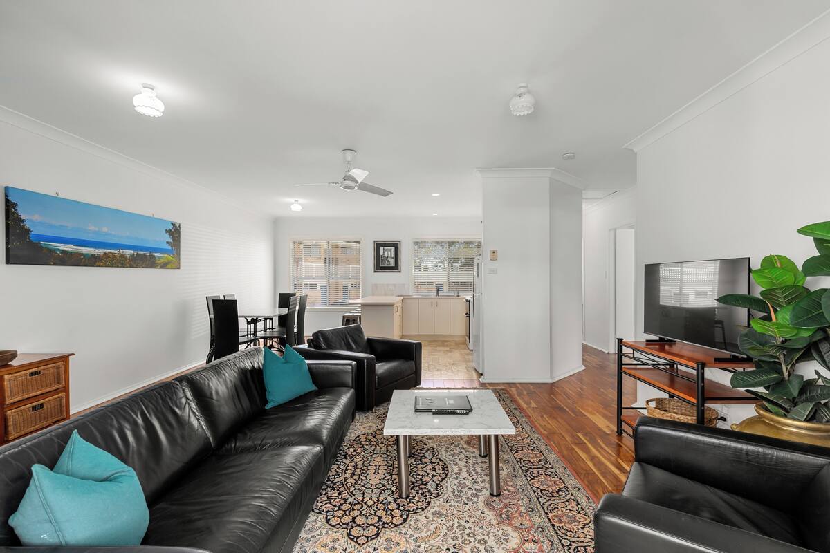 A modern living room with a black leather sofa, a coffee table, and a TV stand.