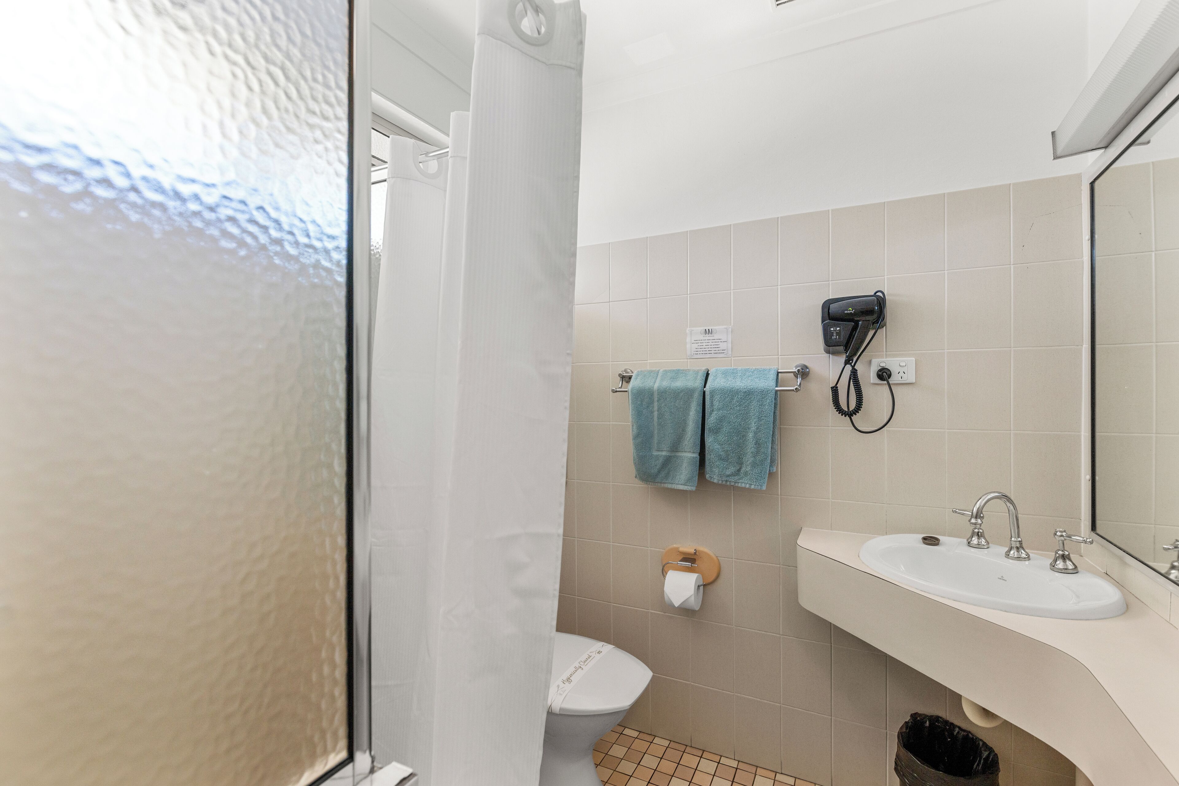 Ein Badezimmer mit Dusche, Toilette, Waschbecken und Handtuchhalter.