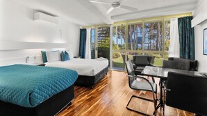 Une chambre d’hôtel moderne dotée d’un grand lit, d’un bureau avec une chaise et d’un balcon offrant une vue sur l’extérieur.