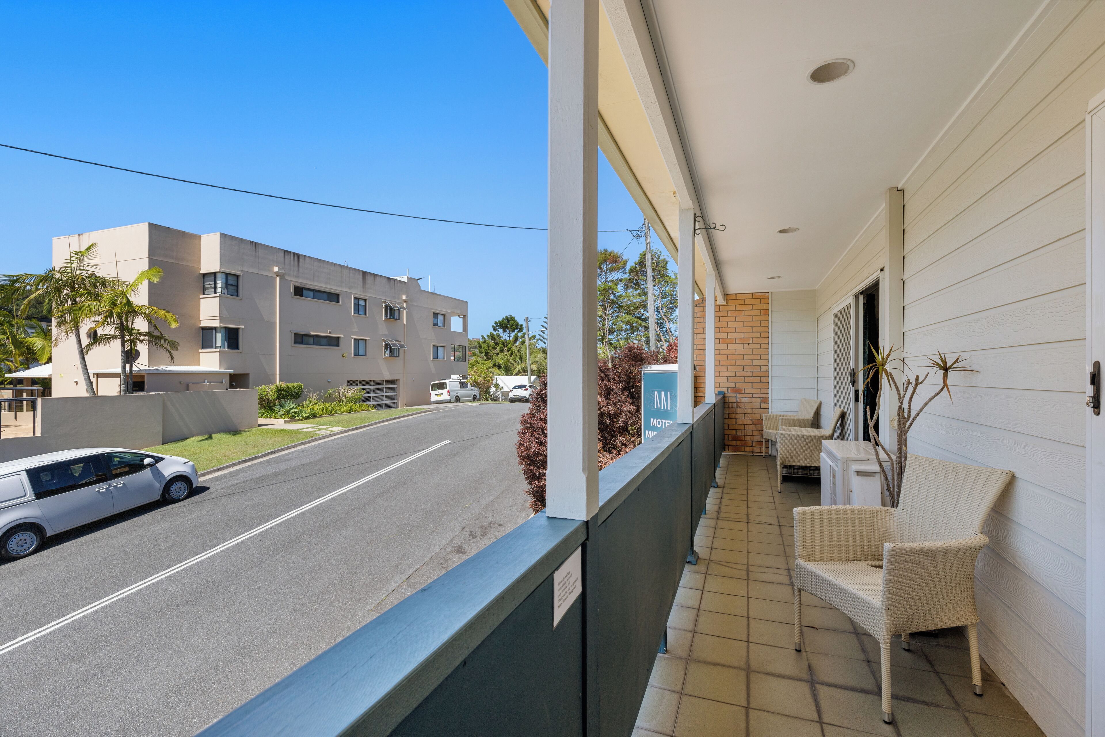 A balcony with a view of a street, a building, and a sign that reads "ANI MOTEL".