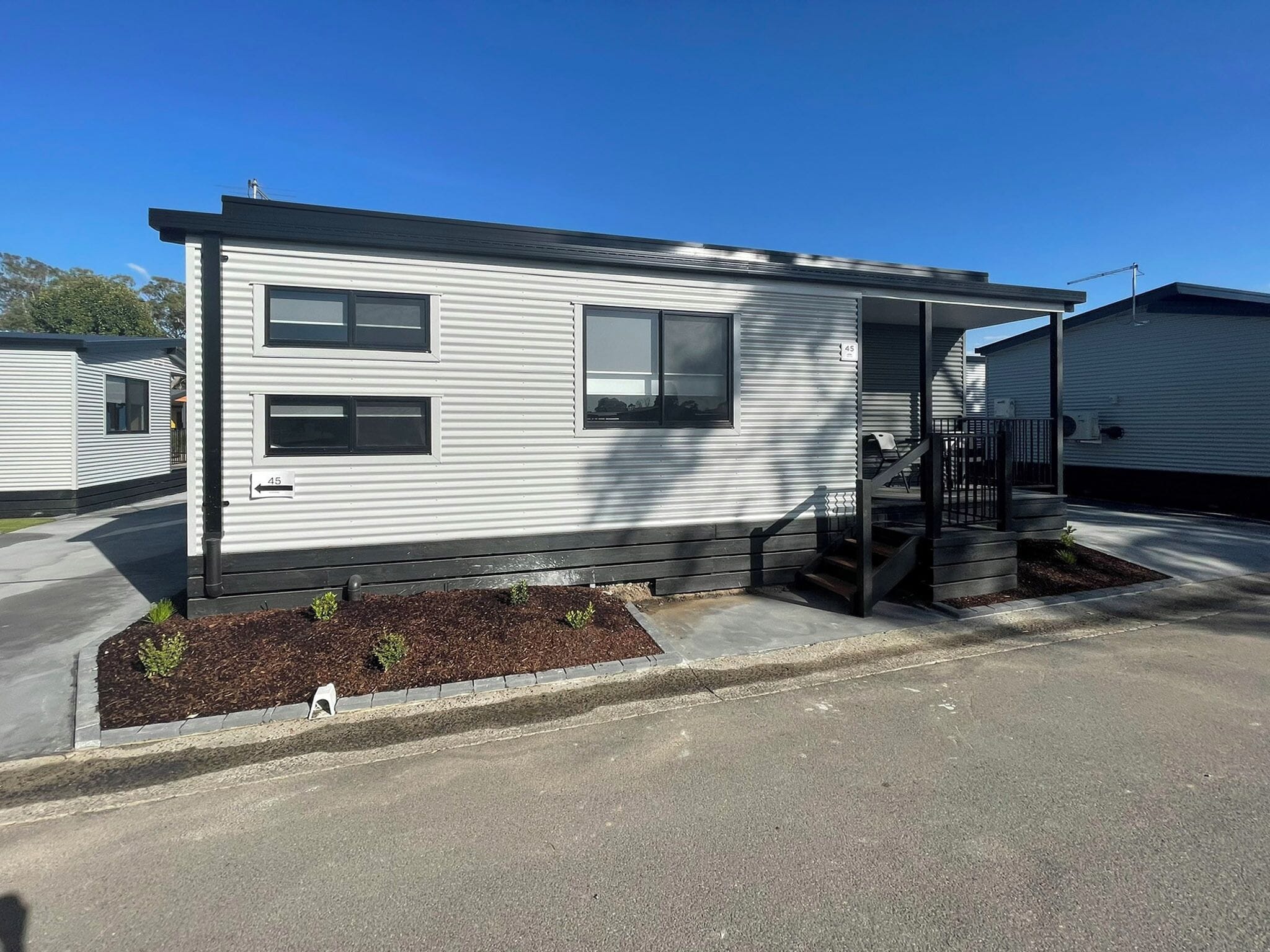 A single-story mobile home with a front porch and a small garden area.