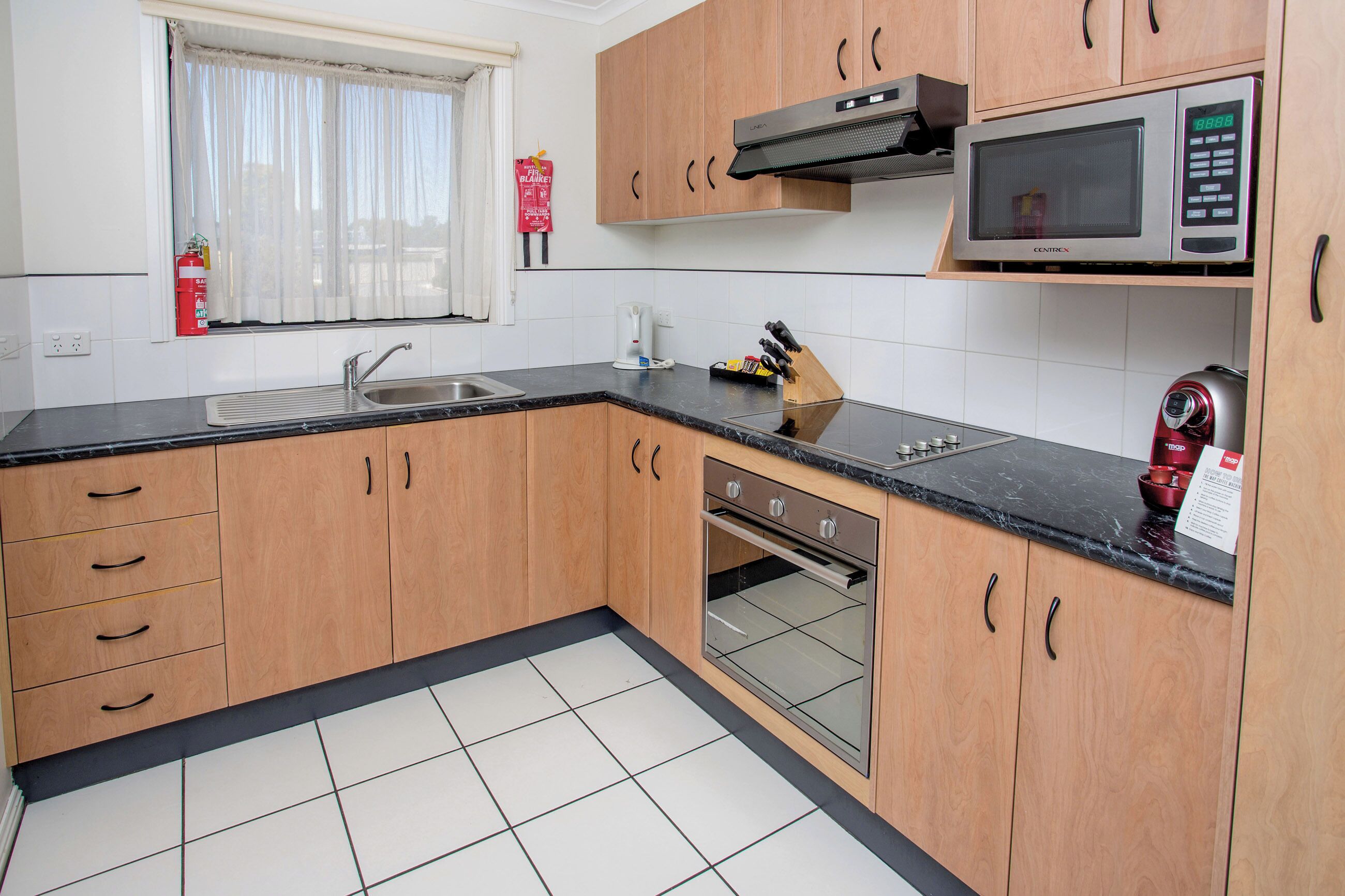 A modern kitchen with wooden cabinets, a stainless steel sink, a microwave, and an oven.