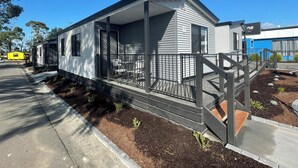 Una casa móvil de un piso con porche cubierto y zona de estar exterior amurallada.