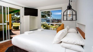 Un dormitorio moderno con una cama grande, un ventanal corredero que da a un espacio exterior y un televisor instalado en la pared.