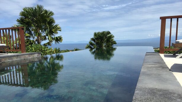 A clear infinity pool with a view of the ocean and mountains. - Villa Ali Agung (Pecatu)
