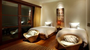 A hotel room with two beds, wicker chairs, a large sliding glass door, and a wall-mounted light fixture. - Villa Ali Agung (Pecatu)