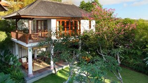 A two-story house with a balcony, surrounded by lush greenery and a well-maintained garden. - Villa Ali Agung (Pecatu)