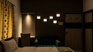 A hotel room with a bed, a desk, a chair, and a wardrobe. - Simi International - The Imperial (Bidhannagar)