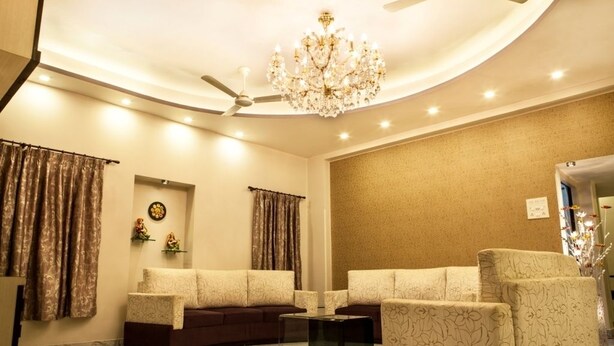 A living room with a sofa set, a coffee table, a chandelier, and a ceiling fan. - Simi International - The Imperial (Bidhannagar)