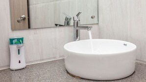 A bathroom with a white sink, a mirror, and a soap dispenser. - Simi International - The Imperial (Bidhannagar)