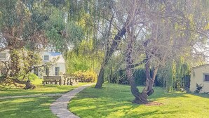 A well-maintained lawn with a winding pathway, a white picket fence, and a bench in the background. - Clonmara Country House & Cottages (Port Fairy)