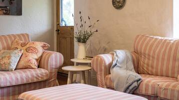 Ein gemütliches Wohnzimmer mit gestreiften Sofas, einem kleinen runden Tisch und einer Vase mit Blumen.