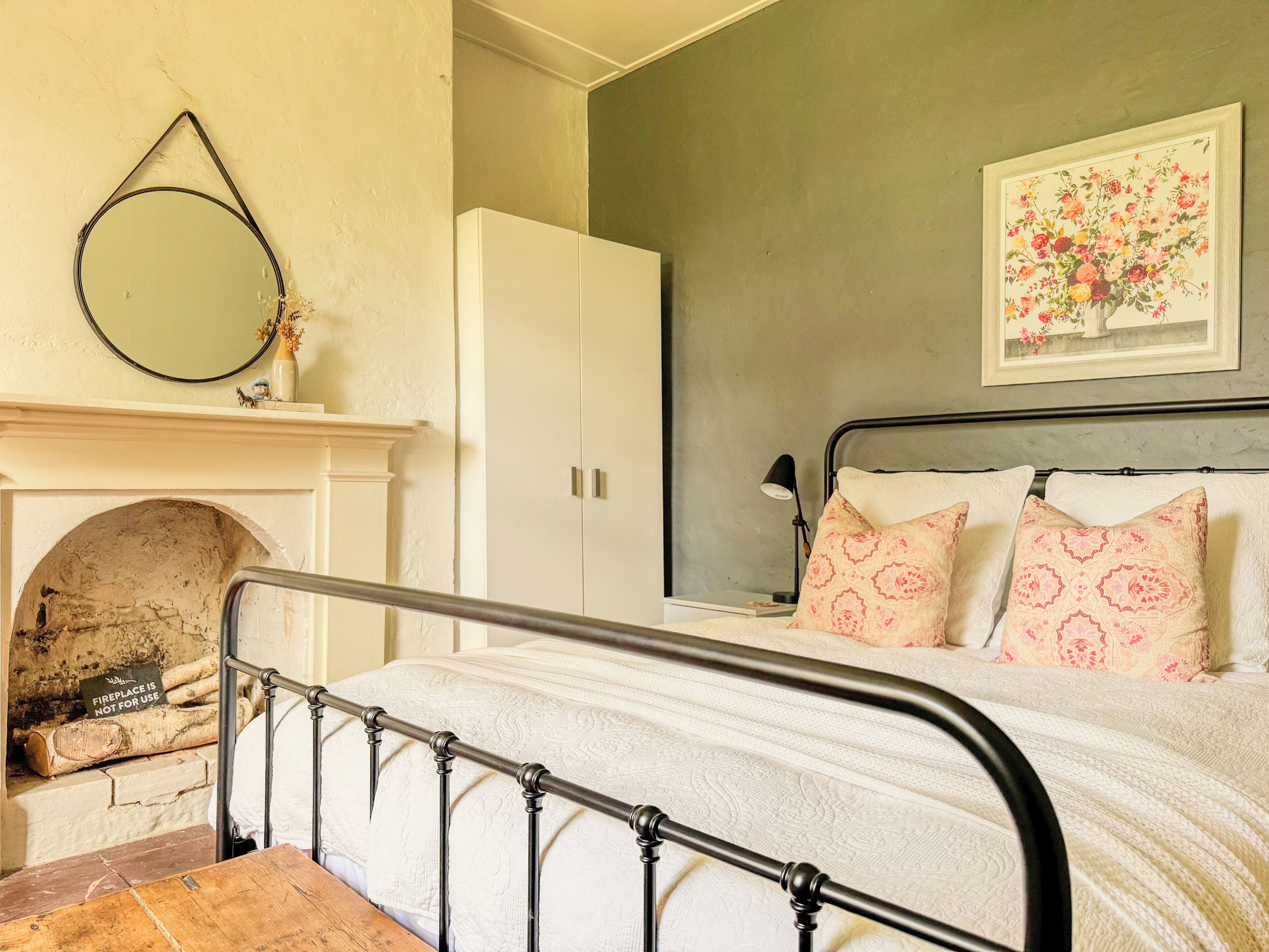 Une chambre à coucher avec un lit, une cheminée, une armoire et un tableau au mur.