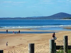 A beach with people, a wooden fence, and a mountain in the background. - Tannum on the Beach Motel (Tannum Sands)