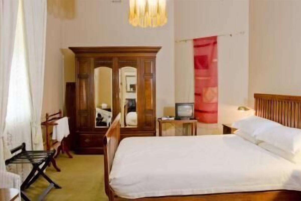 Une chambre d’hôtel avec un lit, une armoire en bois, une télévision et un miroir.