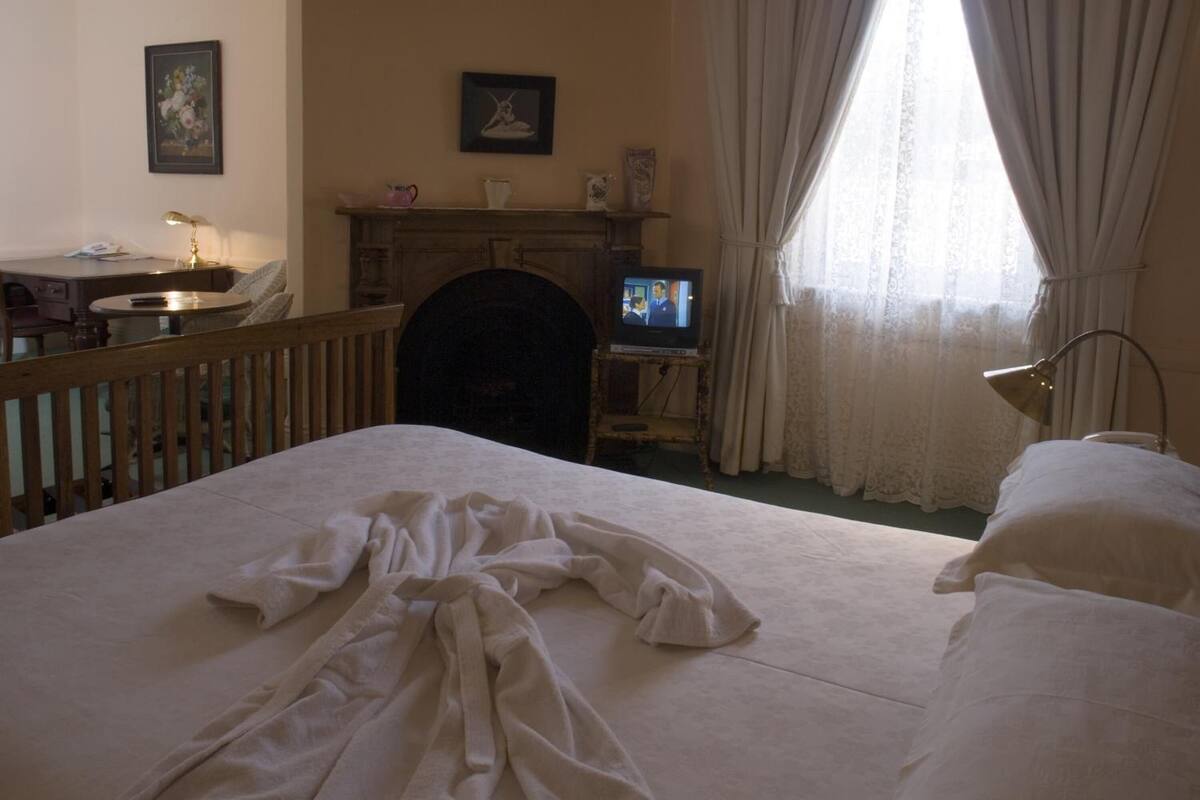 Une chambre d’hôtel équipée d’un lit, d’un bureau, d’une télévision et d’une cheminée.