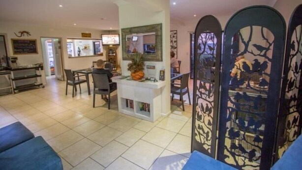 A hotel lobby with a reception desk, seating area, and decorative panels. - Spinifex Motel & Serviced Apartments (Townview)