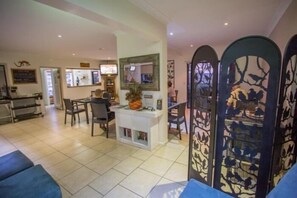 A hotel lobby with a reception desk, seating area, and decorative panels. - Spinifex Motel & Serviced Apartments (Townview)