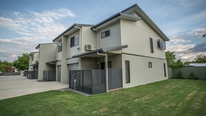 A modern two-story residential building with a flat roof, a covered patio, and a fenced yard. - Spinifex Motel & Serviced Apartments (Townview)