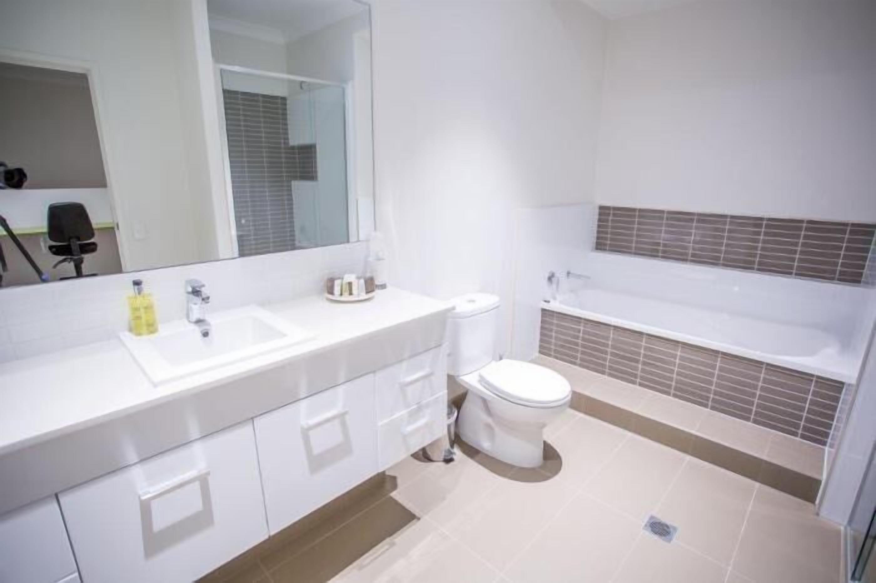 A modern bathroom with a white sink, toilet, and bathtub.