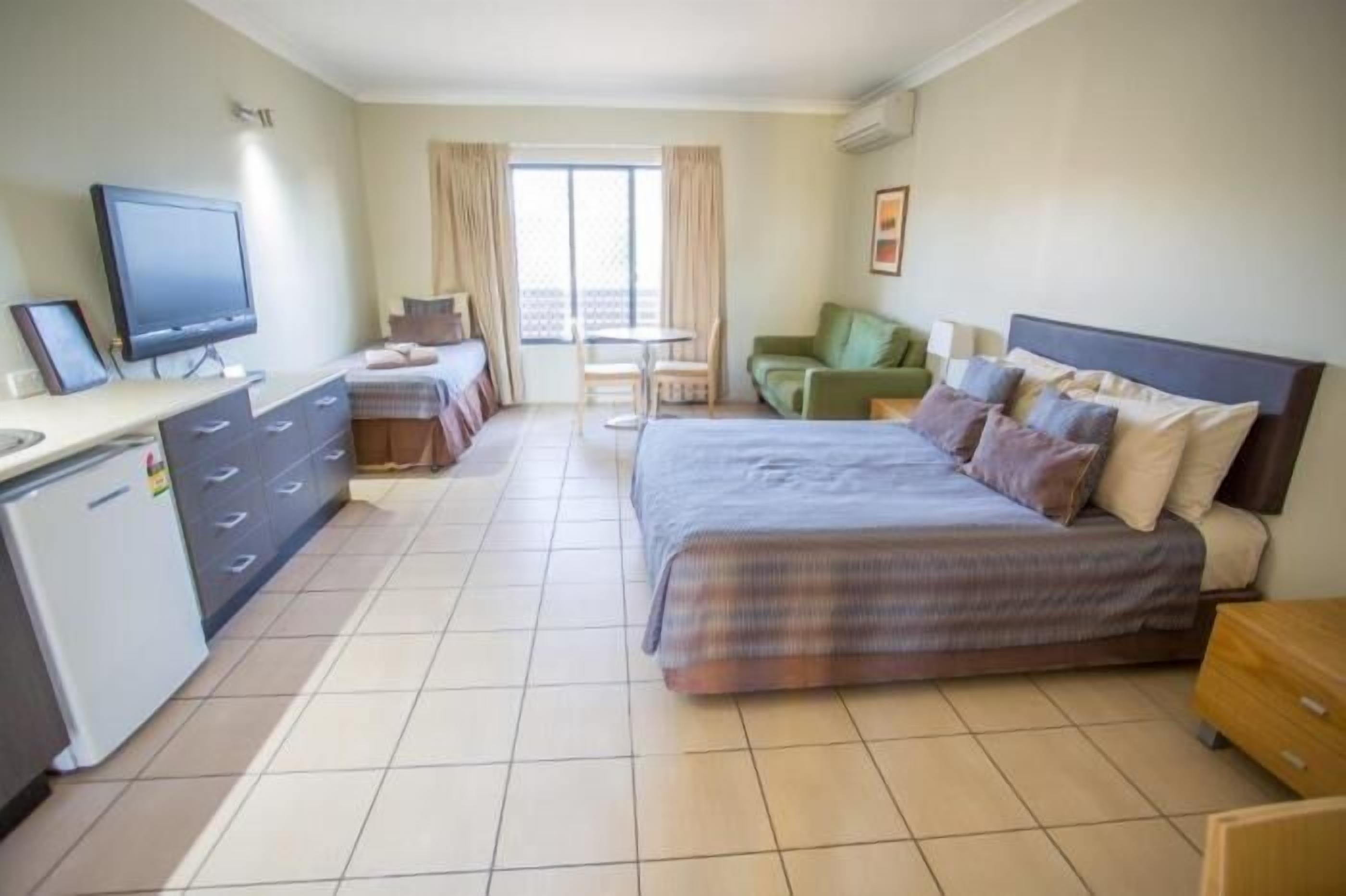 A hotel room with a bed, a desk, a television, and a view of the outside.