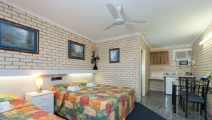 Una habitación con dos camas, un escritorio, una silla, un ventilador de techo y un microondas.