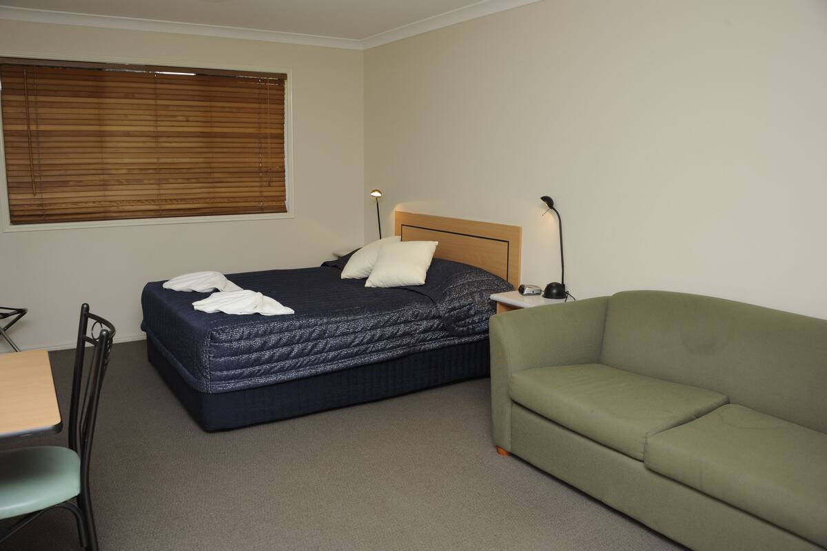 Ein Hotelzimmer mit einem Bett, einem grünen Sofa, einem Schreibtisch und einem Sessel.