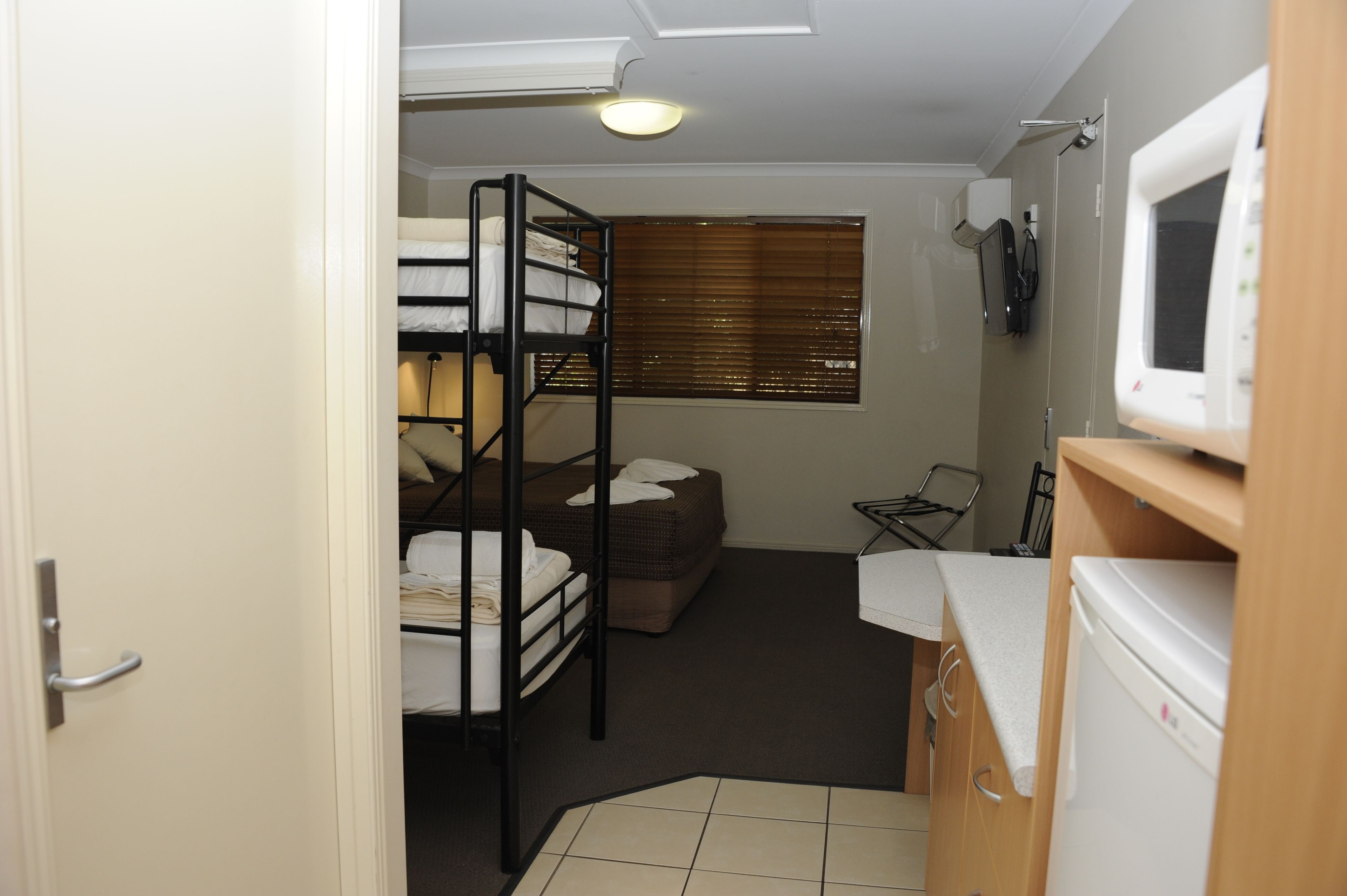 A compact room with bunk beds, a small sofa, a television, and a refrigerator.