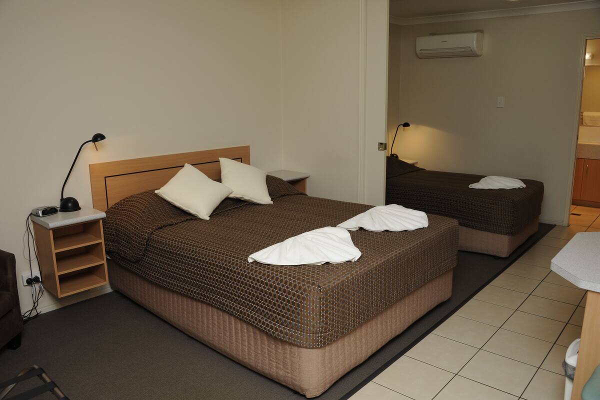Ein Hotelzimmer mit einem großen Bett, einem Nachttisch, einer Lampe und einem kleinen Schreibtisch.