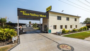 Ein Motel Eingang mit deutlicher Beschilderung, einem gepflasterten Zufahrtsweg und einem kleinen Garten.