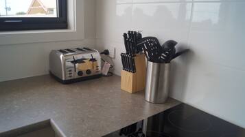 A kitchen with a toaster, a knife block, and a stove.