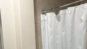 Een badkamer met een wit wastafel, een glazen plank, een handdoekhouder met een witte handdoek en een douchegordijn.