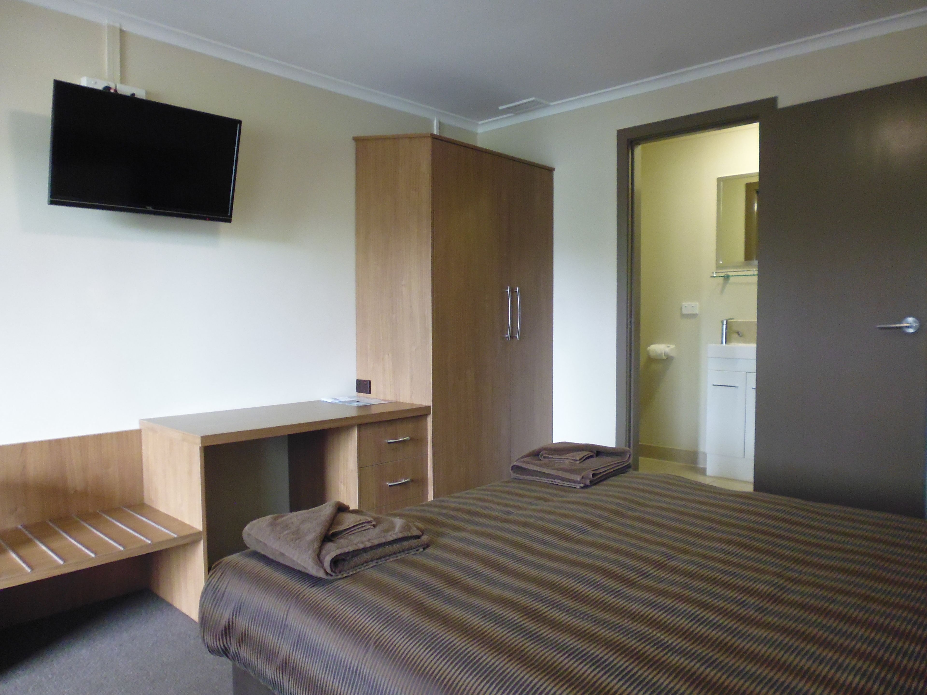 Une chambre d’hôtel équipée d’un lit, d’un bureau, d’une armoire et d’un téléviseur.