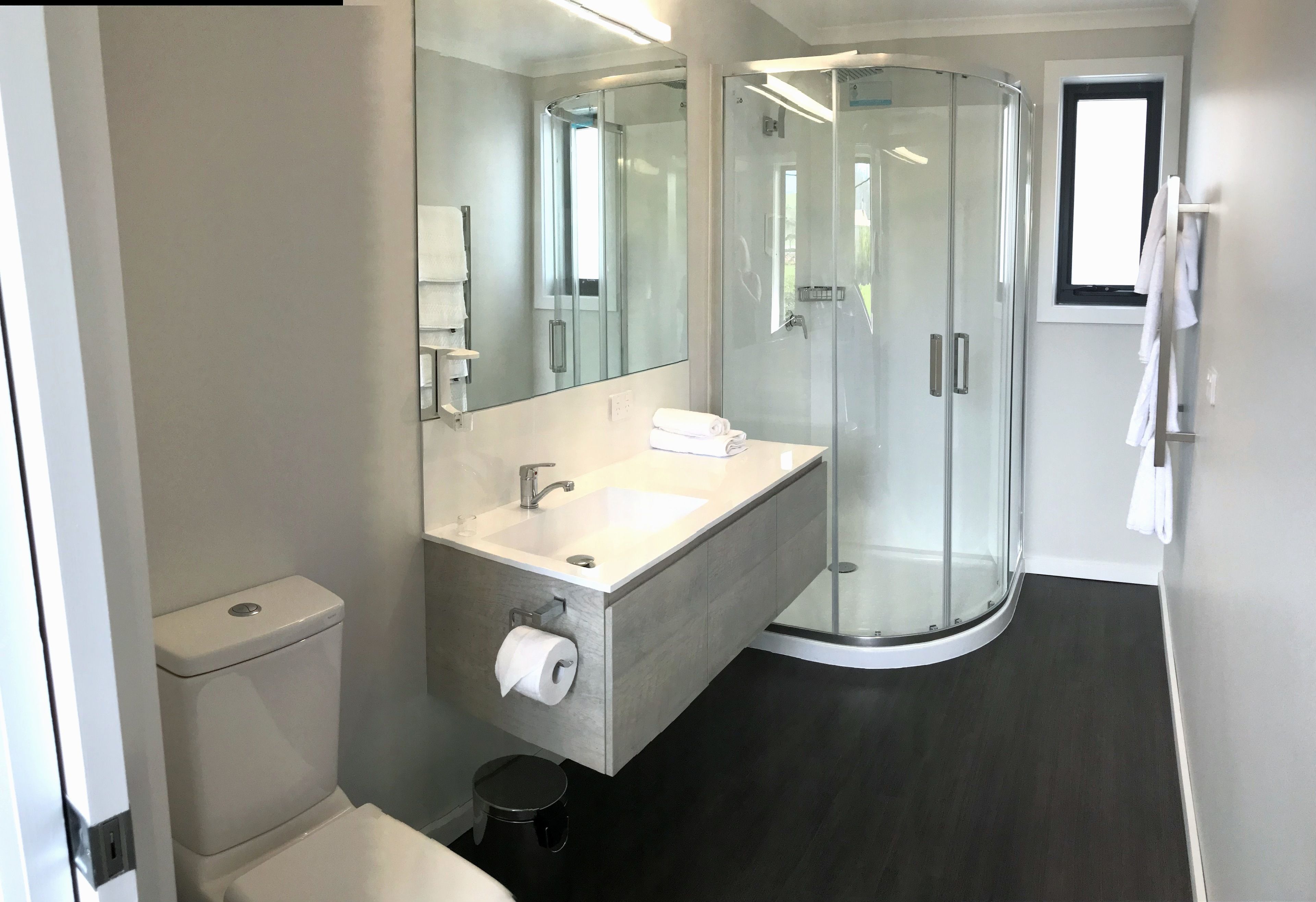 Une salle de bain moderne avec une douche à parois de verre, un lavabo blanc et des toilettes.
