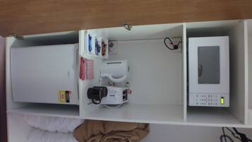 Una kitchenette equipada con microondas, cafetera y refrigerador pequeño.